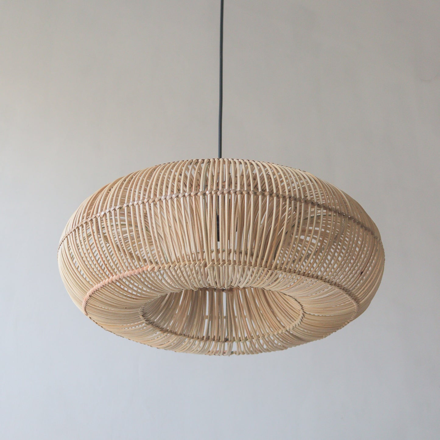 Handcrafted rattan pendant light in donut design, showcasing unique artisanal craftsmanship from Bali, Indonesia.