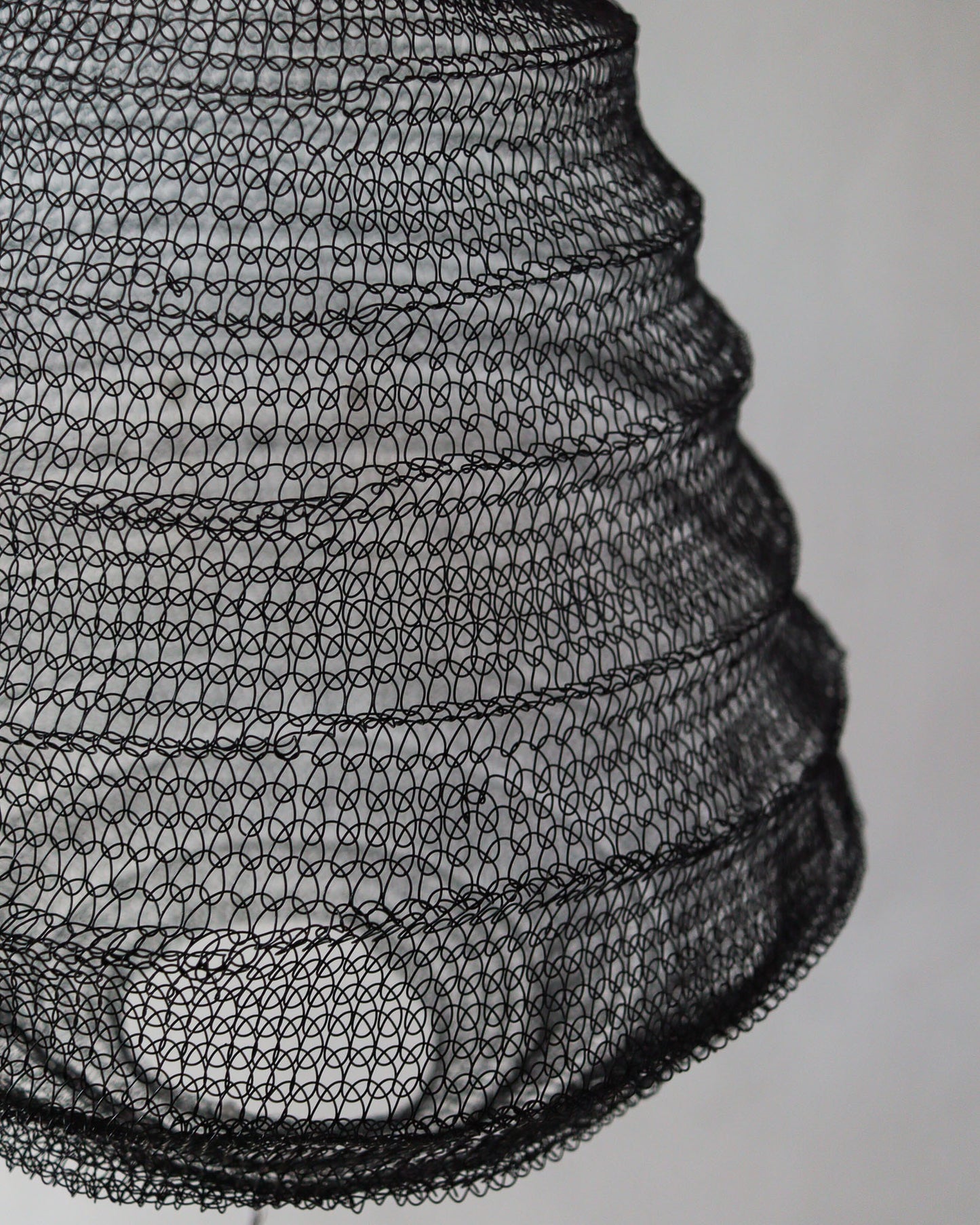 Close-up of a black wire mesh chandelier showcasing a beehive design, handcrafted with intricate detailing.