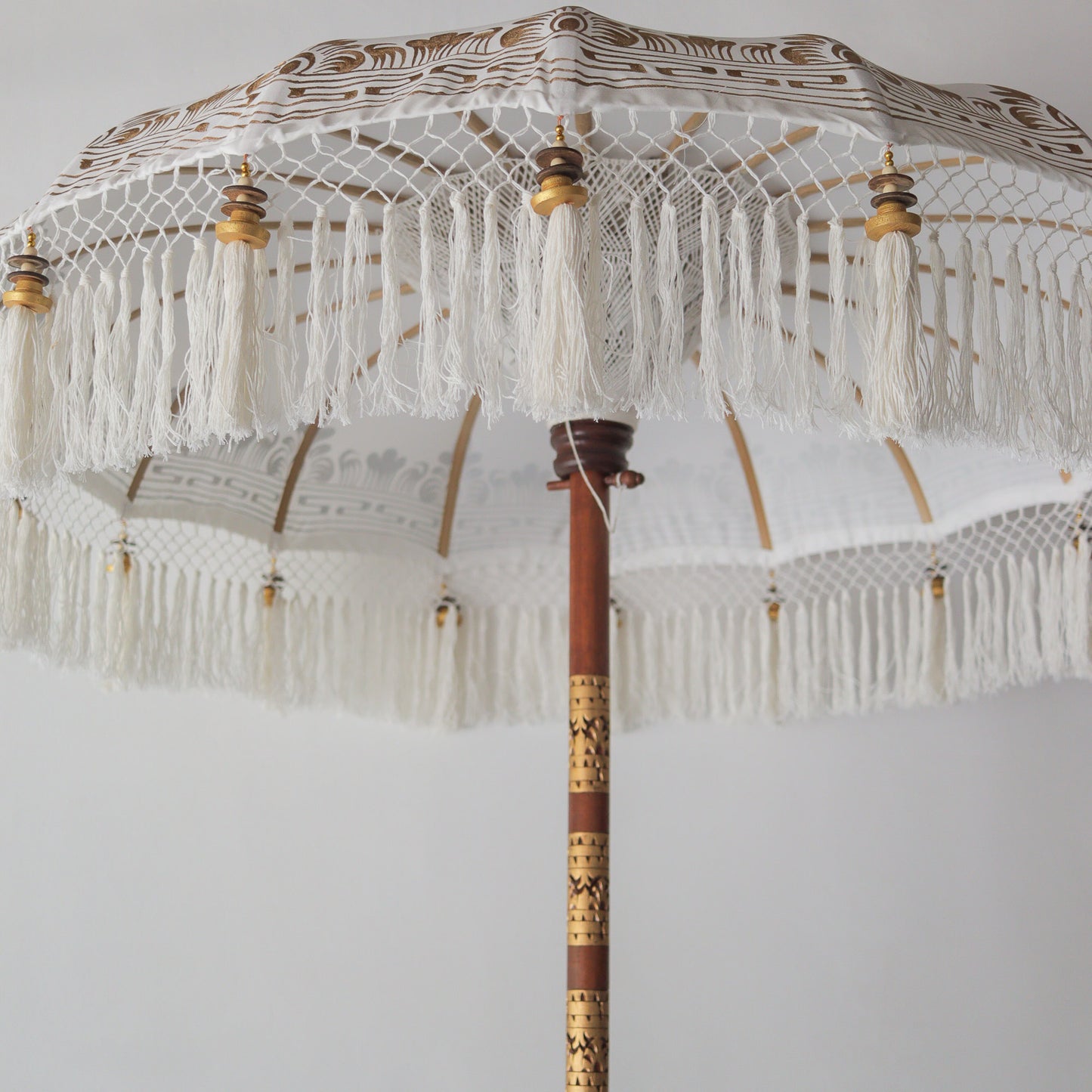 Hand painted Balinese parasol in white with intricate tassels, perfect for home decor or events.