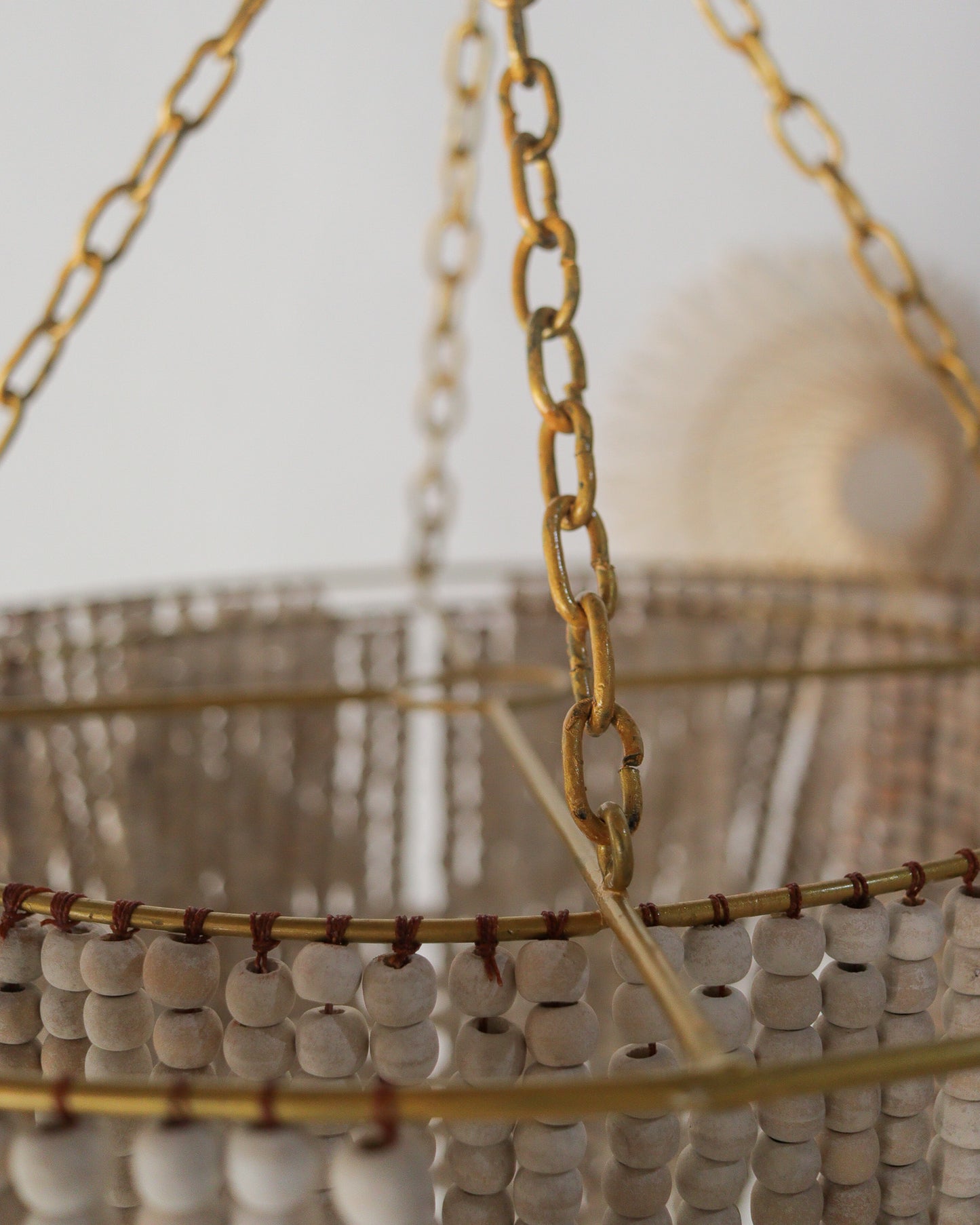 Beaded chandelier in gold and white, handcrafted in Bali, featuring a unique design and rustic charm.