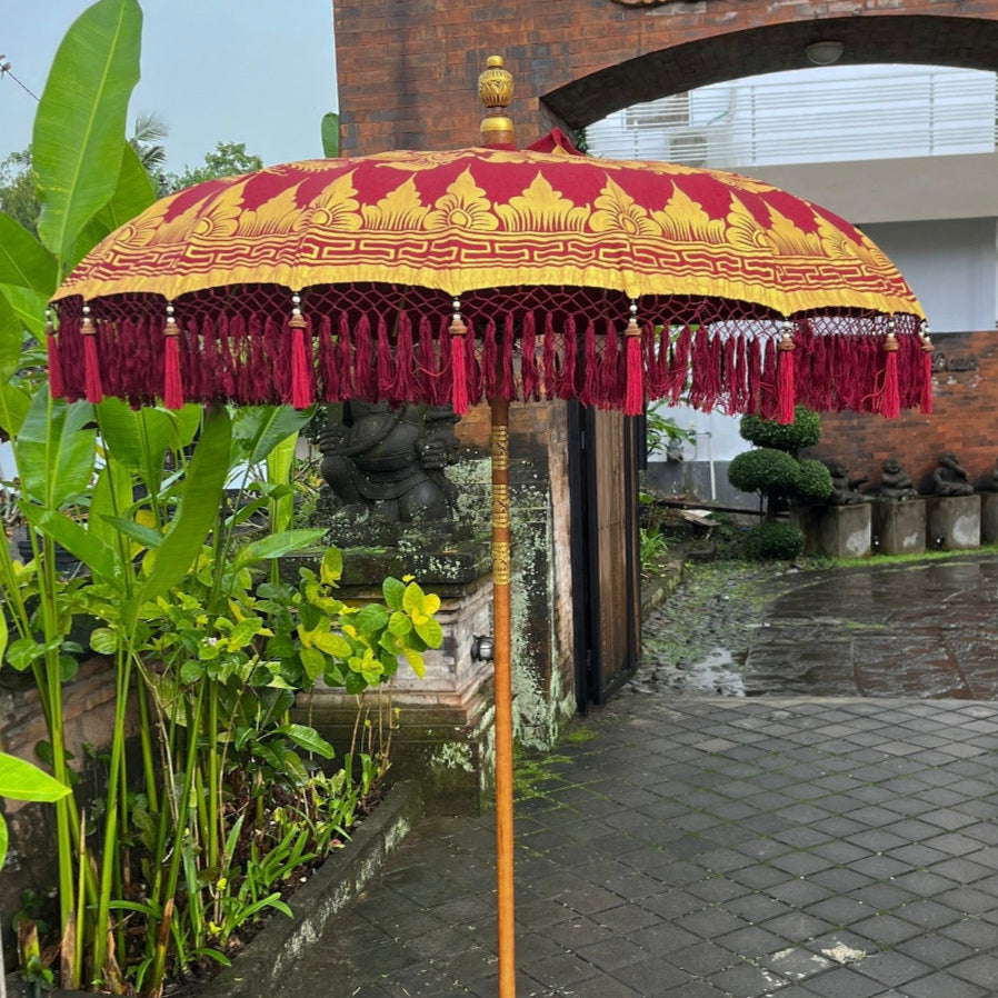 Decorative umbrella with red and gold canopy on a stone pathway