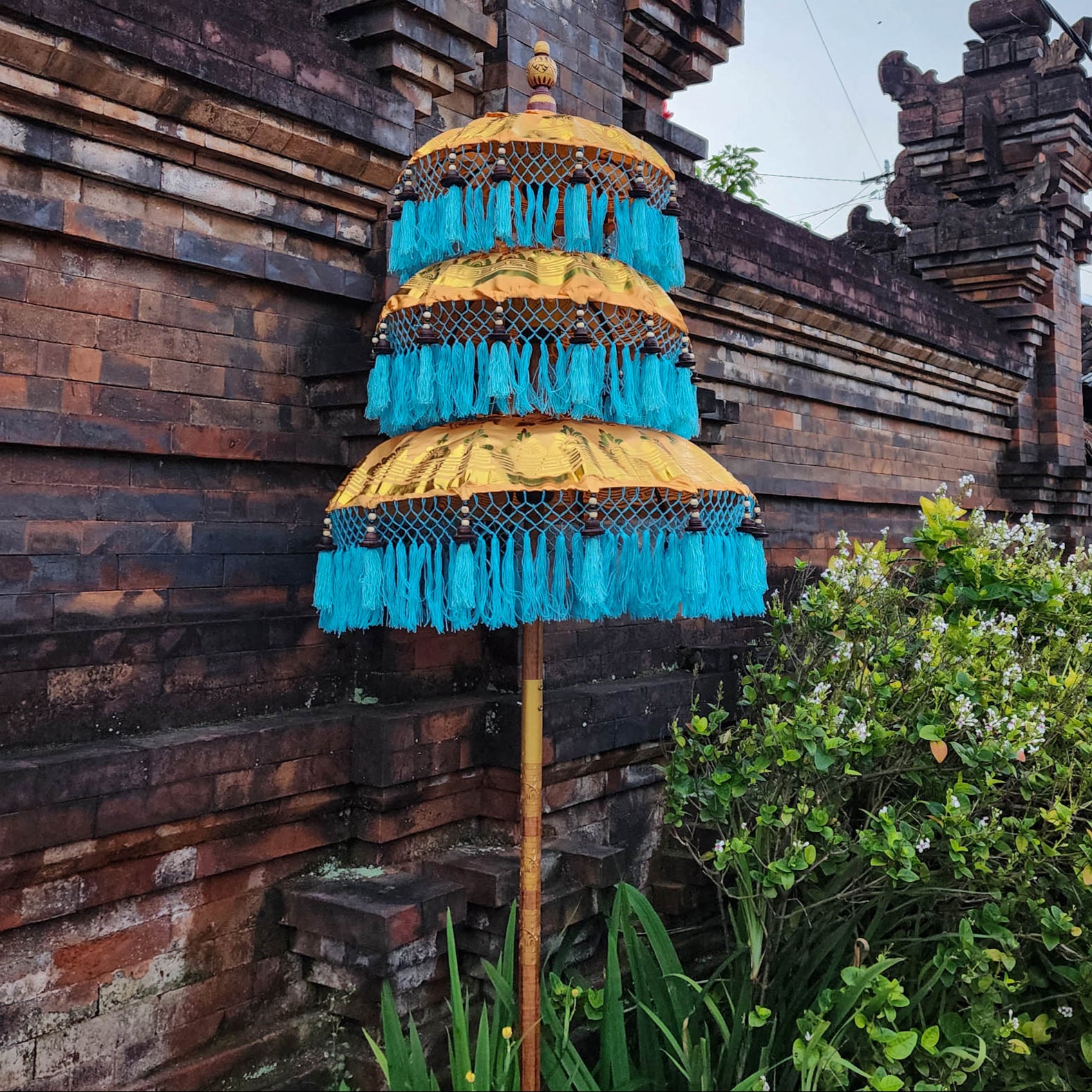 Decorative umbrella with blue fringes in front of a traditional wooden building
