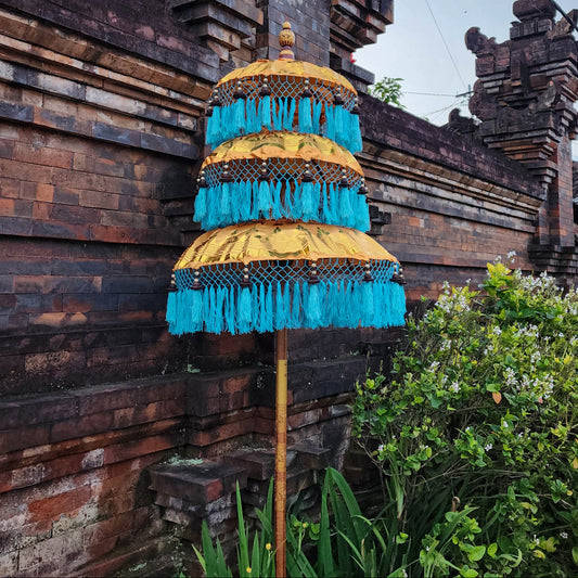 Decorative umbrella with blue fringes in front of a traditional wooden building
