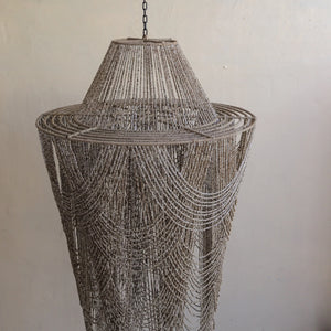 Balinese chandelier with cascading beige beads against a neutral wall