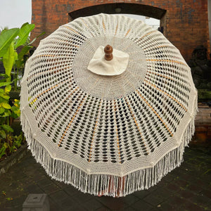 Balinese macrame umbrella with intricate boho style handmade fringe in outdoor setting