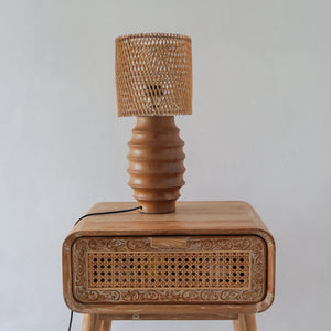 Handcrafted rattan table lamp on carved wood nightstand, boho bedroom decor