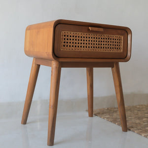 Handcrafted wooden bedside table with woven rattan drawer in minimalist room