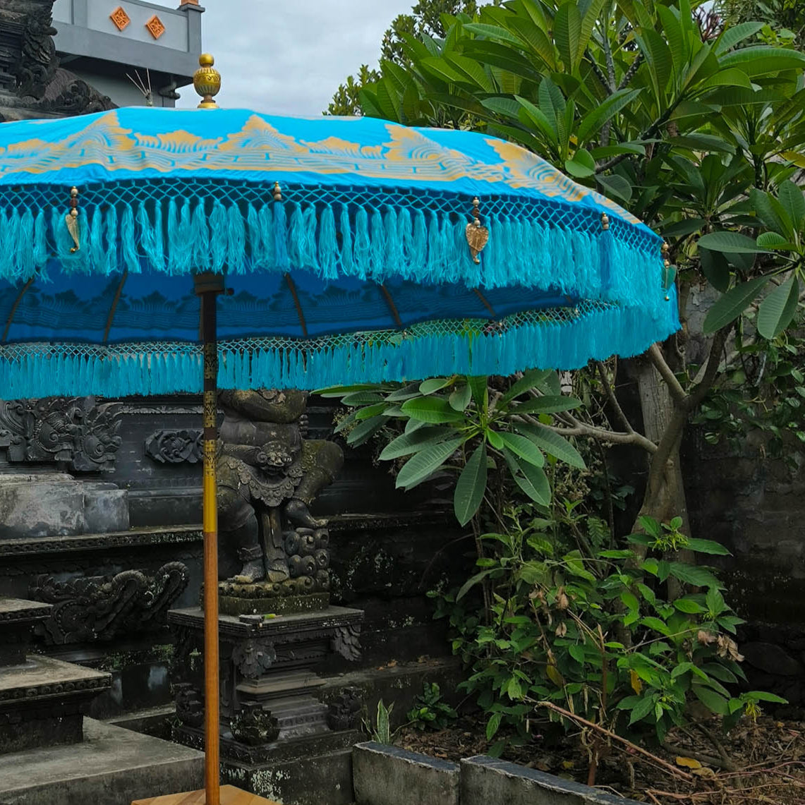 Blue decorative umbrella with gold accents in front of a temple structure.