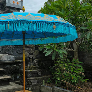 Blue decorative umbrella with gold accents in front of a temple structure.
