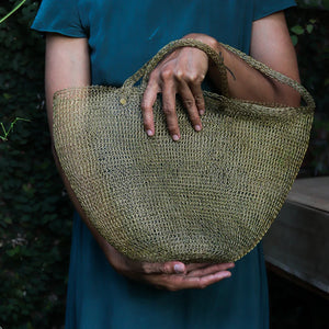 Person holding a woven bag outdoors