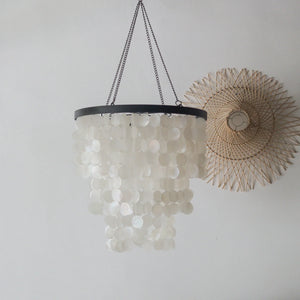 Capiz Shell chandelier in black and white, crafted in Bali, hanging elegantly against a wall decor.