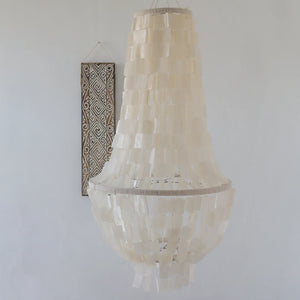 Capiz shell chandelier hanging in a minimalist room with tribal wall art decor.