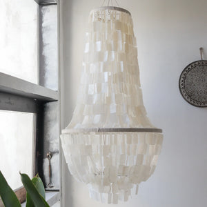 Handmade capiz shell chandelier with layered white shells hanging in a bright modern room