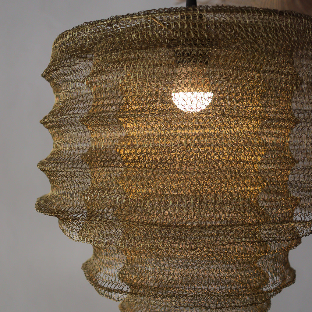 Textured gold pendant light against a neutral background
