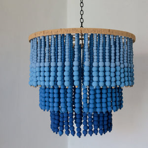 Blue beaded chandelier with ombre effect, hanging in a modern minimal room