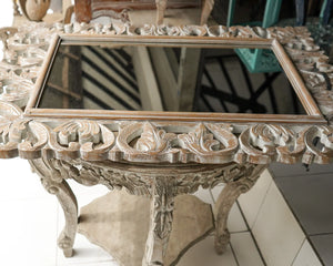 Hand-carved wooden table with ornate floral detailing and a rectangular glass top
