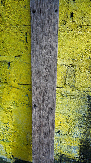 Textured wood plank mounted on a rough yellow brick wall, rustic home decor background