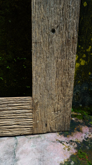 Close-up of weathered hand-carved wooden door frame with rustic texture and natural finish