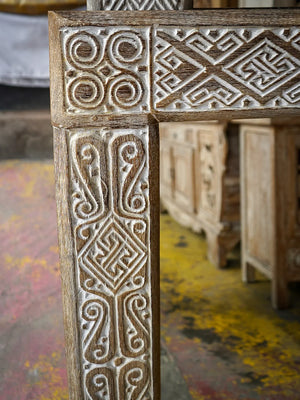 Hand-carved wooden furniture detail with intricate Balinese patterns and whitewash finish