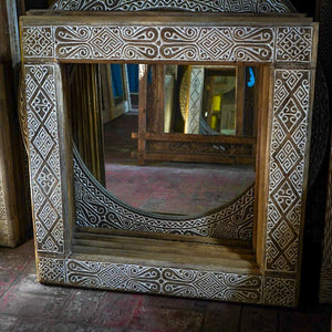 Hand-carved wooden mirror with intricate Balinese patterns and rustic finish