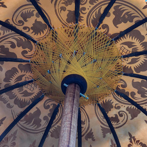 Close-up of decorative Balinese umbrella with intricate patterns and wooden pole