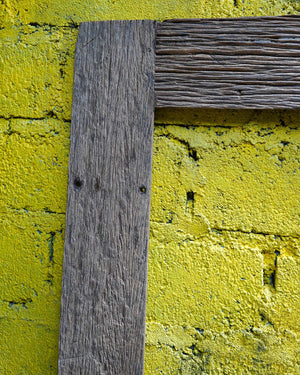 Close-up of reclaimed teak wood frame against textured yellow brick wall