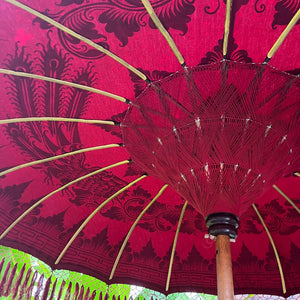 Detail of a red Balinese umbrella with intricate patterns and bamboo spokes