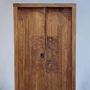 Hand-carved wooden door with intricate Balinese floral design, luxury entryway decor