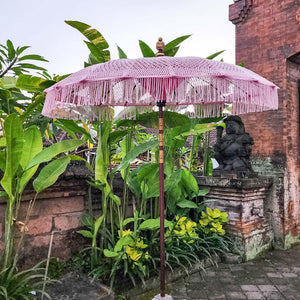 Handcrafted Balinese garden umbrella with fringe in tropical outdoor setting