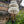 Handcrafted Balinese parasol with white fringe by a traditional stone wall and greenery