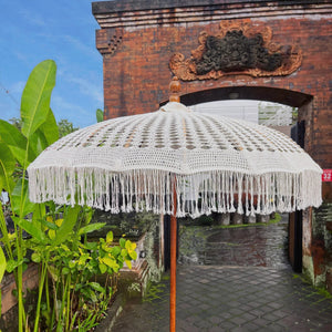 Handmade Balinese macrame parasol with fringe, set in a tropical outdoor entrance.