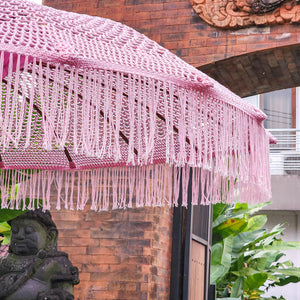 Handmade Balinese umbrella with pink fringe, outdoor setting, tropical decor