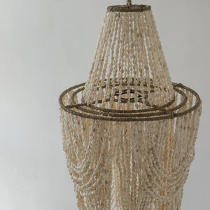 Handmade Balinese seashell chandelier with natural rope detailing against a neutral wall