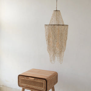 Boho seashell chandelier and hand-carved wooden nightstand in minimalist room