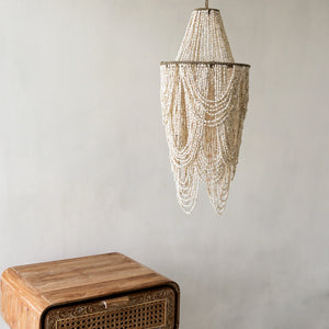 Handmade seashell chandelier with intricate beaded strands above a carved wooden table