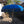 Balinese blue ceremonial umbrella with fringe, outdoors by traditional carved stone decor