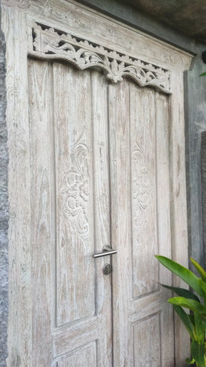 Hand-carved Balinese wooden door with floral patterns and decorative trim