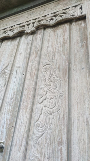 Hand-carved Balinese wooden door with intricate floral and scrollwork details