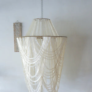 Hand-carved seashell chandelier with cascading shells and tribal wall art in minimalist room