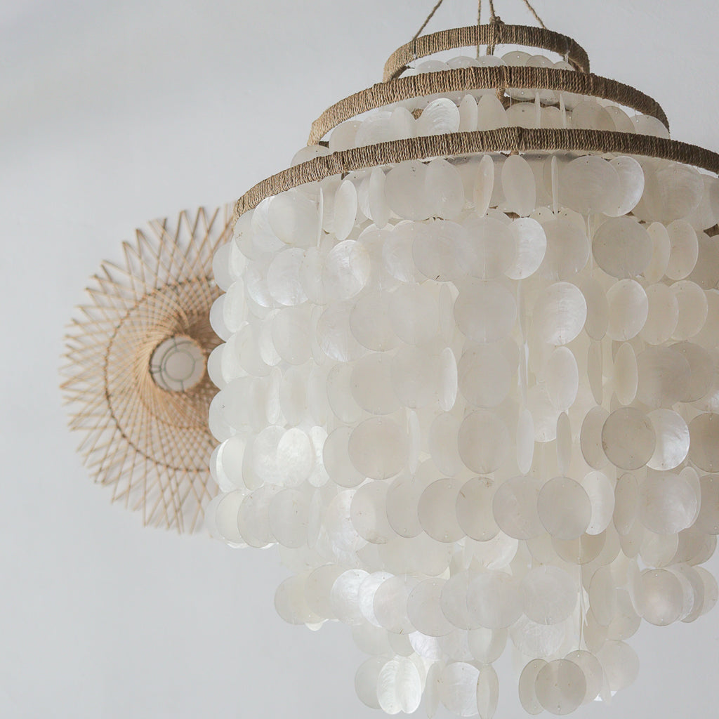 Decorative chandelier made of white shell-like material on a plain background