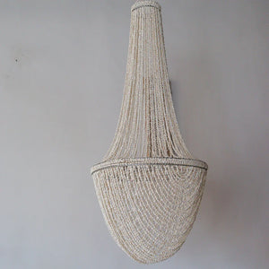 Handmade Balinese seashell chandelier with intricate bead strands on a plain wall