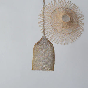 Handwoven rattan pendant light with intricate sunburst bamboo wall decor on white wall