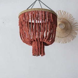Handmade terracotta beaded chandelier with boho style, hanging against a white wall
