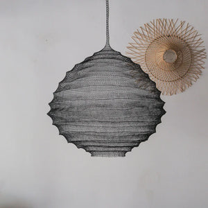 Handmade black rattan pendant light and woven bamboo wall decor on white wall