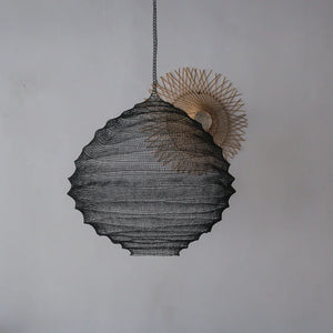 Handmade black rattan pendant lamp with natural woven accent against a plain wall