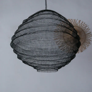 Handcrafted black wire mesh pendant light with modern sculptural design against white wall