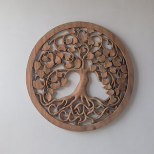 Hand-carved wooden Tree of Life wall art with intricate Balinese design on a white wall.