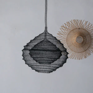 Handcrafted black wire pendant light and rattan wall decor on a minimalist white wall