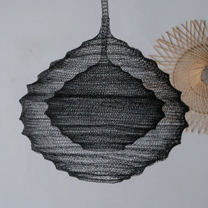Handcrafted black wire pendant lamp with a scalloped design hanging against a plain wall