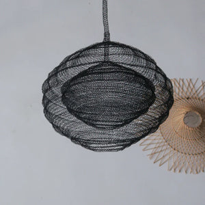 Handcrafted black wire pendant lamp with a modern round design, hanging against a light wall